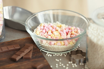 Glass bowl with crispy rice balls, marshmallow and chocolate bars on table
