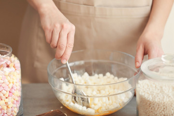 Woman mixing ingredients for rice dessert in glass bowl on table