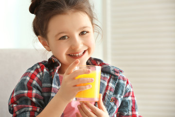 Cute little girl with glass of juice at home