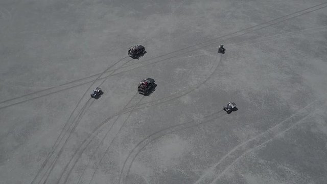 Aerial view of ATV driving down a beautiful wide open beach with crashing ocean waves slow motion
