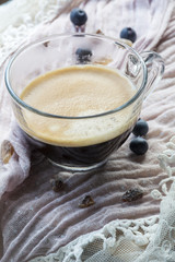 One cup of coffee on the pink tissue with several blueberries and sugar