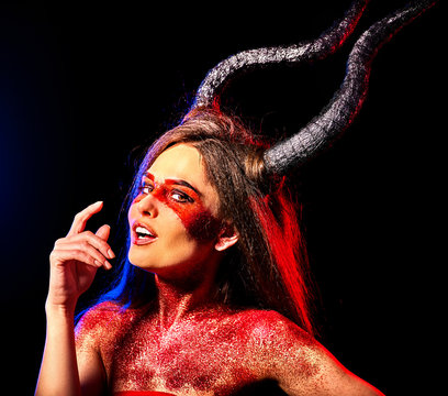 Mad satan woman on black magic ritual of hell. Witch with horns reincarnation mythical creature Sabbath. Halloween dark background. Zodiac Capricorn Aries. Make-up for night club for demon .