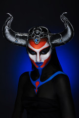 Mystery portrait of female faun with blue eyes, body art and silver snakes on black horns