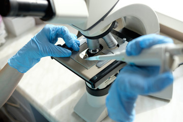 woman laborant working with microscope holding automatic pipette