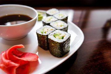 Rolls in nori seaweed with avocado, pickled ginger and soy sauce. Asian cuisine, traditional dish - sushi.