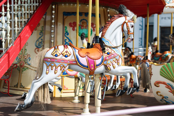 Fototapeta na wymiar Horses on a carnival Merry Go Round. Old French carousel in a holiday park. Big roundabout at fair in amusement park.