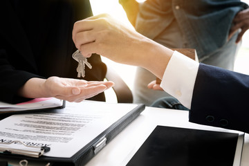 estate agent giving house keys to man and sign agreement in office