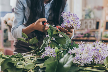 close-up partial view of florist cutting flowers with secateurs - Powered by Adobe