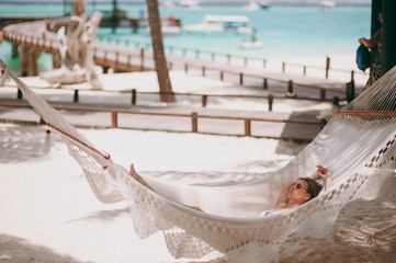 Beautiful girl lies in a hammock on the beach