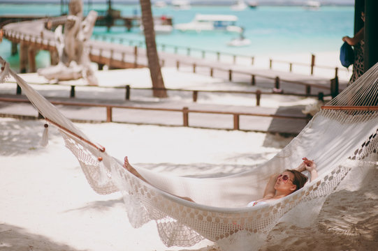 Beautiful girl lies in a hammock on the beach