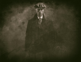 Antique wet plate photo of threatening 1920s english gangster in smoky room.