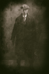 Fototapeta premium Antique wet plate photo of threatening 1920s english gangster holding gun in smoky room.