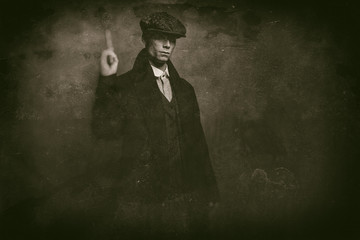 Antique wet plate photo of dangerous 1920s english gangster standing with gun.