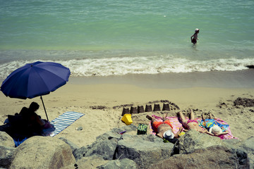 Different kinds of enjoyment on the Black Sea beach in the umbrella shadow, sunbathing on the hot sand or playing in the water.