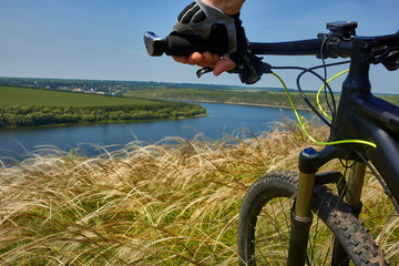 Cyclist travel on mountain bike through green meadow against beautiful sky.