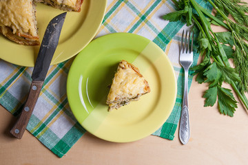 Piece of pancakes pie with mushrooms and chicken meat on green plate and metal fork. Traditional meal for Maslenitsa - Russian pancake week..