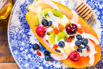 Breakfast with papaya fruit bowl with yogurt, berries, nuts.