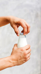 Man holding a bottle of milk on gray background.