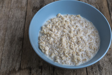 Oatmeal porridge in bowl for breakfast on rustic wooden table
