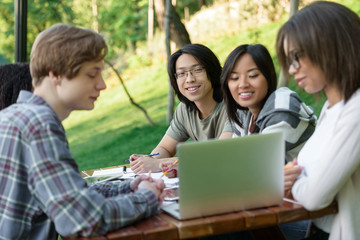 Multiethnic group of happy young students studying outdoors