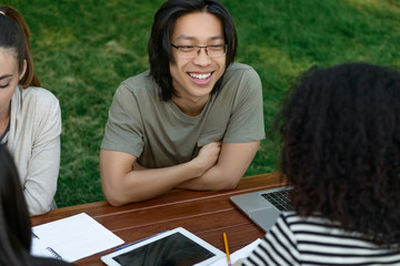 Happy young students sitting and studying outdoors