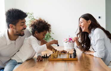 Happy family playing chess together at home