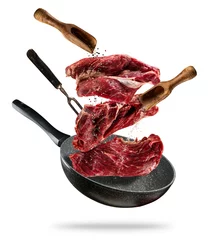 Fotobehang Vlees Flying raw steaks with cooking ingredients from pan