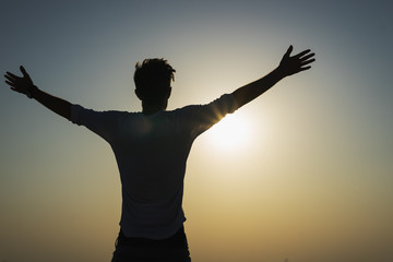 Silhouette of a happy man is strong confidence open arms under the sunset om the top. Freedom and...