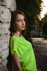 beauty portrait of young beautiful girl posing against stone wall and green ivy
