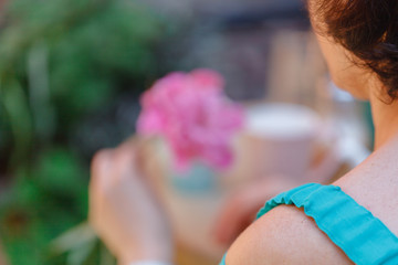 Naklejka premium Woman hold one peony flower in street cafe