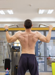 bodybuilder man pull up on fitness machine, doing back muscle exercise