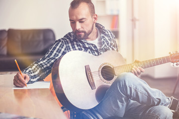 Serious bearded man looking at his writing hand