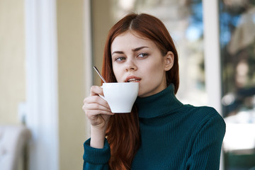 Young beautiful woman drinks coffee in a cafe on the street