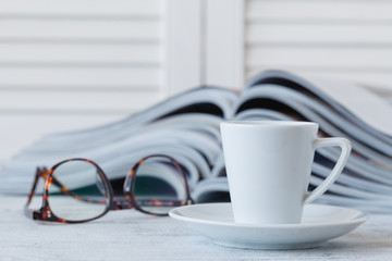 White cup with morning beverage and magazine on the wood table