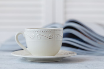glossy magazine on a table, with coffee cup Very shallow depth of field