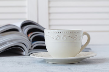 Cup of coffee with magazines on wooden background