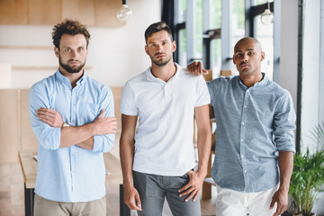 multiethnic young businessmen looking at camera while standing in office