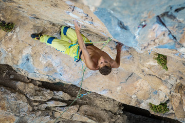 sportsman Dmitrii Fakirianov climbs an overhang rock and grips the hold