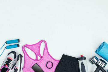 Sportswear with sneakers, smartphone, fitness tracker and fitness equipment isolated on grey