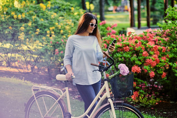 Obraz premium A woman with city bicycle in a summer outdoor park.
