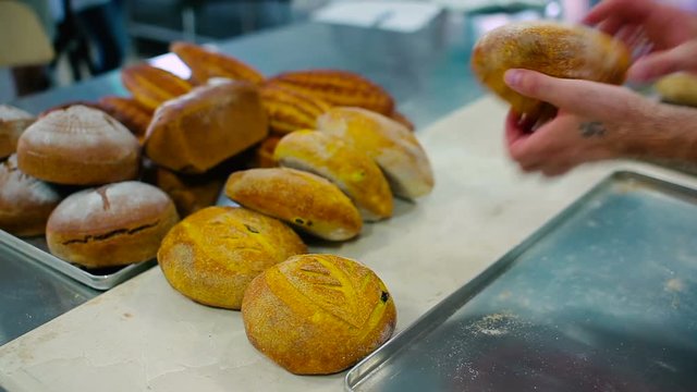 The bread at the table in the kitchen. The cook put another one bread and two small near the all bread.