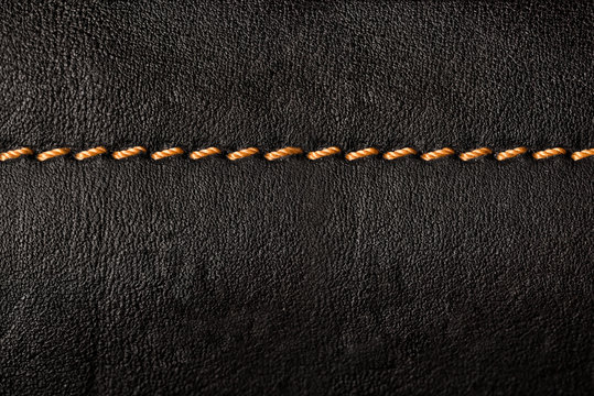 Black leather texture background with orange seams