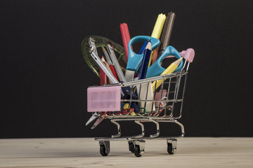 Back to school template with multiple stationery in trolley against black
