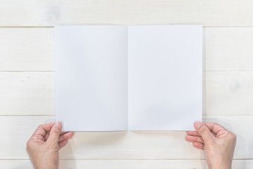 Obraz premium Mock up flyer pamphlet brochure design A5 size paper in business man's hand for template illustration mockup, flat lay on wood table from top view