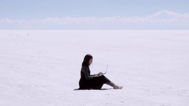 Hispanic woman working on the salt flats of Uyuni in Bolivia. Digital nomad working as freelance writer. 4k