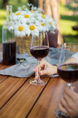 Cropped picture of women sitting outdoors in park drinking wine