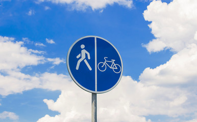 Round, blue sign of a walkway for bicycles and pedestrians on a cloudy background