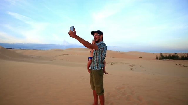 Father Holds Small Girl Makes Selfie on Dunes at Sunset