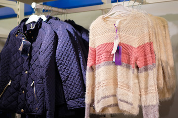 Kids sweaters and winter jackets on hangers in kids store