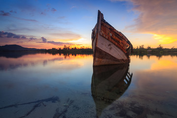 Abandon Old wreck on the shore , Borneo , Old fishing boat with the reflection on sunset momment